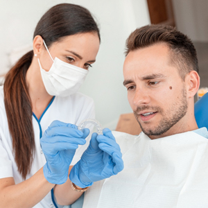 A dentist showing a male patient how an Invisalign aligner works