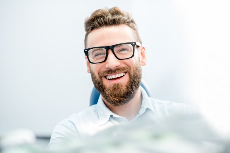 a man with glasses and dental implants smiling 